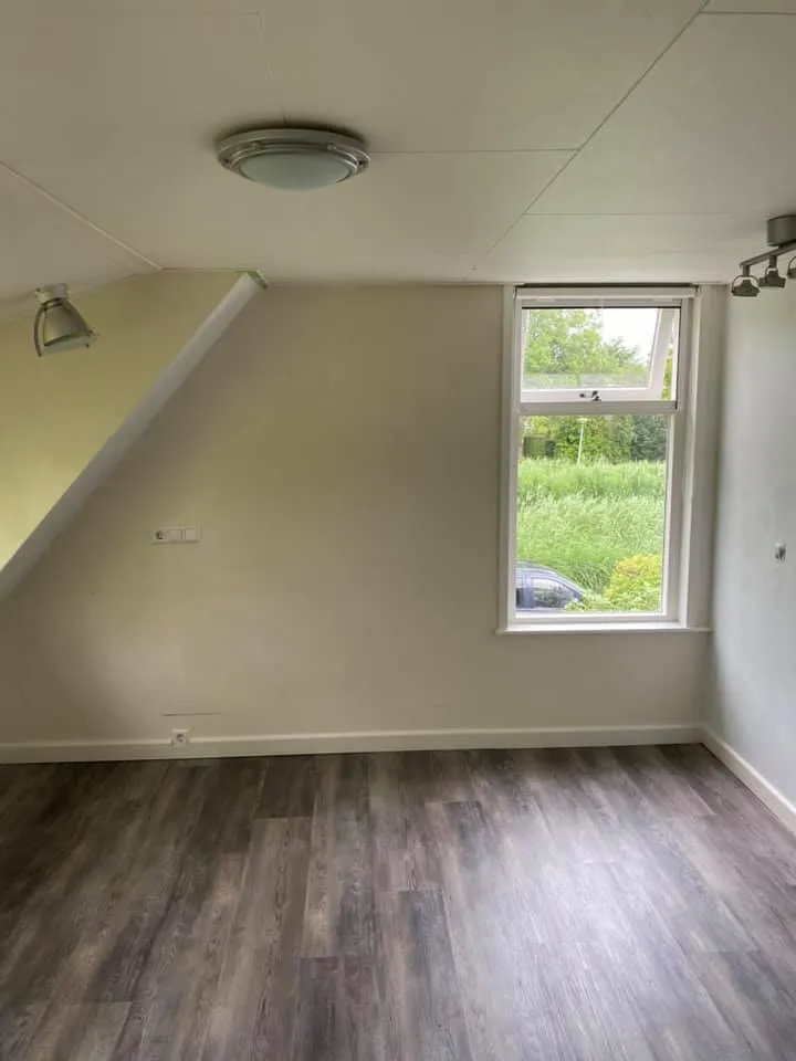 Afgewerkte kamer met lichte muren en laminaat