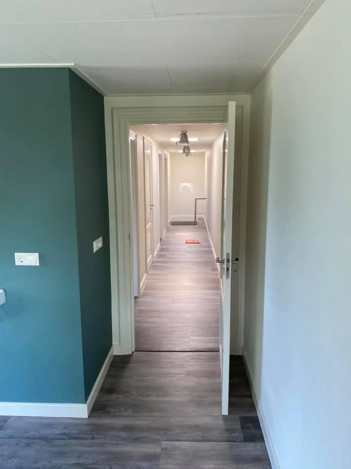 Gang met turquoise accentmuur en laminaatvloer