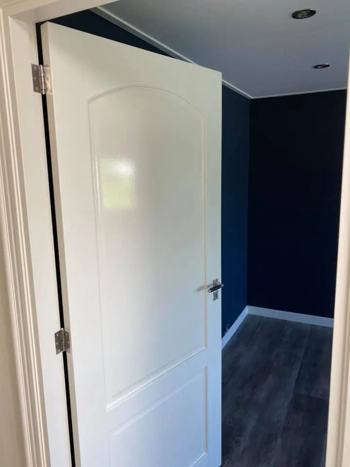 Witte deur naar kamer met donkerblauwe muren